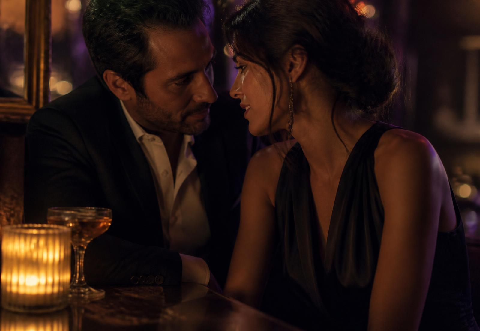 A couple in close conversation at a candlelit bar